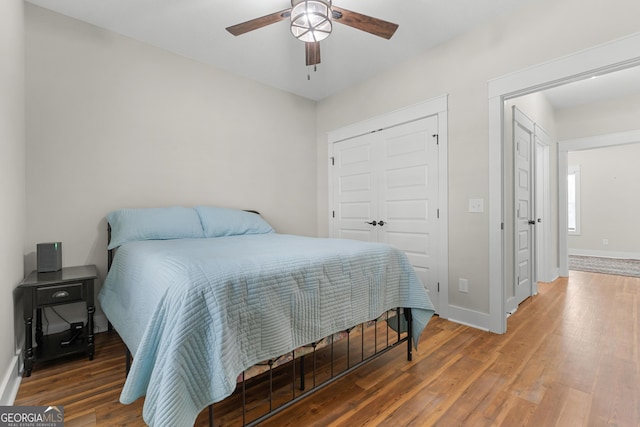 bedroom featuring a ceiling fan, wood finished floors, a closet, and baseboards