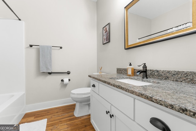 bathroom with toilet, vanity, baseboards, and wood finished floors