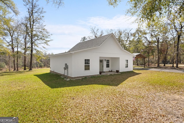 rear view of property with a yard and roof with shingles