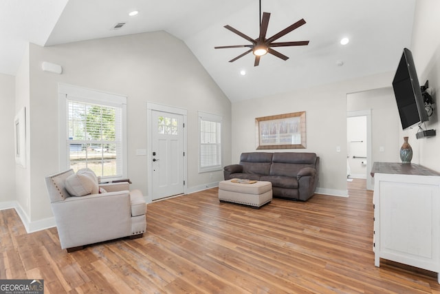 living area with visible vents, baseboards, ceiling fan, light wood-style flooring, and high vaulted ceiling