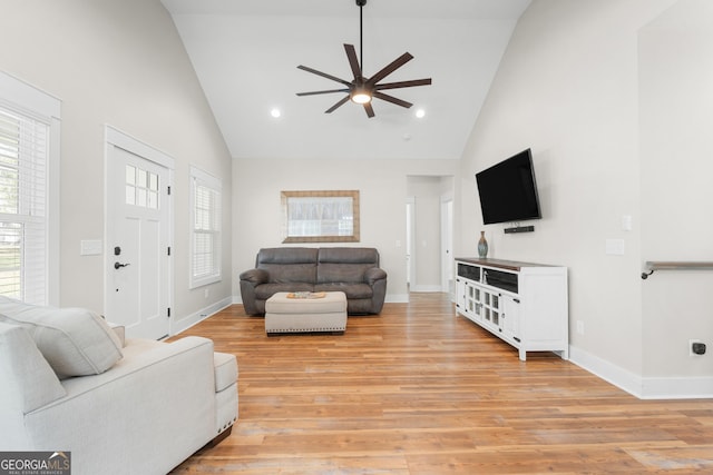 living room with light wood-style floors, a healthy amount of sunlight, and high vaulted ceiling