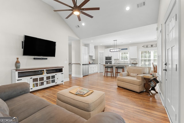 living room featuring baseboards, visible vents, high vaulted ceiling, recessed lighting, and light wood-type flooring