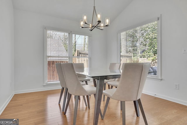 dining room featuring a notable chandelier, light wood-style floors, a healthy amount of sunlight, and vaulted ceiling