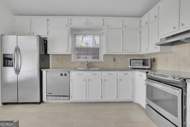 kitchen with under cabinet range hood, decorative backsplash, white cabinets, stainless steel appliances, and a sink