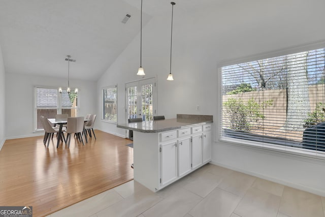 kitchen with visible vents, pendant lighting, white cabinetry, a peninsula, and light wood finished floors