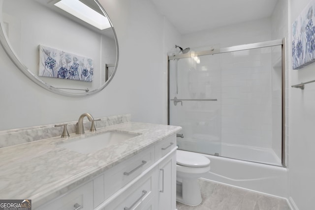 bathroom featuring toilet, vanity, and bath / shower combo with glass door