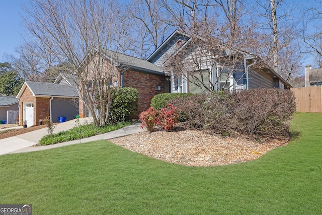 single story home with brick siding, a garage, a front lawn, and fence