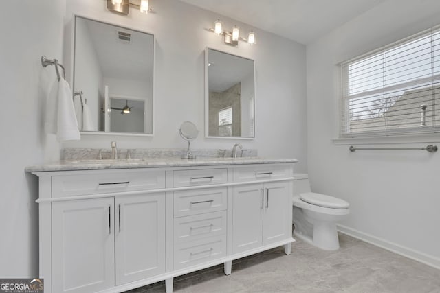 bathroom featuring double vanity, toilet, visible vents, and a sink