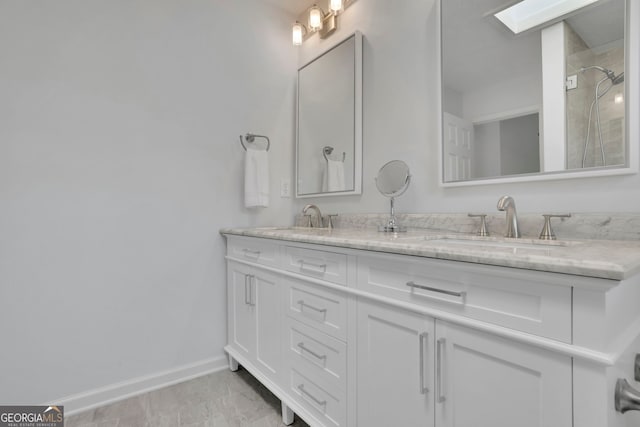 full bathroom featuring double vanity, walk in shower, baseboards, and a sink