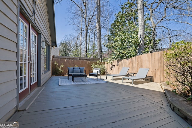 wooden deck featuring an outdoor living space, french doors, and a fenced backyard