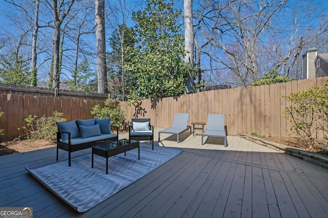 wooden terrace with an outdoor hangout area and a fenced backyard