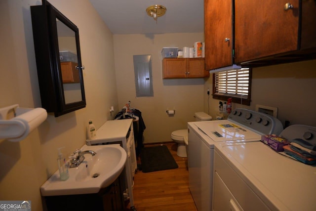 laundry area with independent washer and dryer, electric panel, a sink, wood finished floors, and laundry area