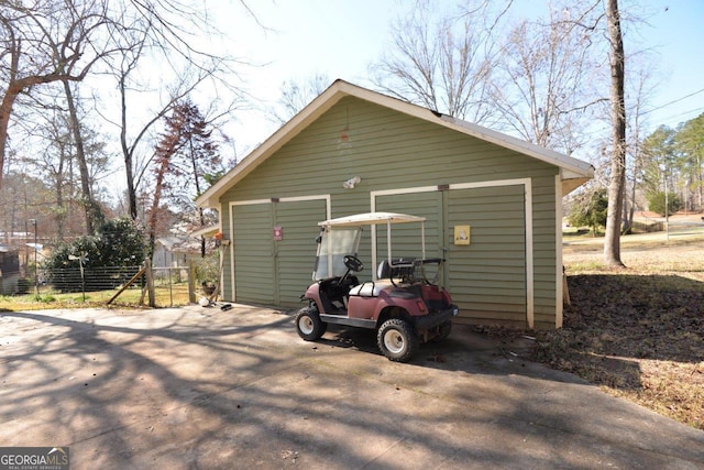 view of outbuilding with a detached carport, an outbuilding, fence, and driveway