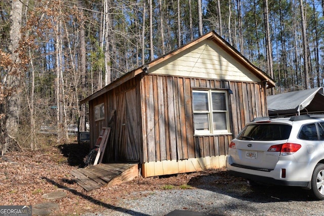 view of property exterior with board and batten siding and a forest view