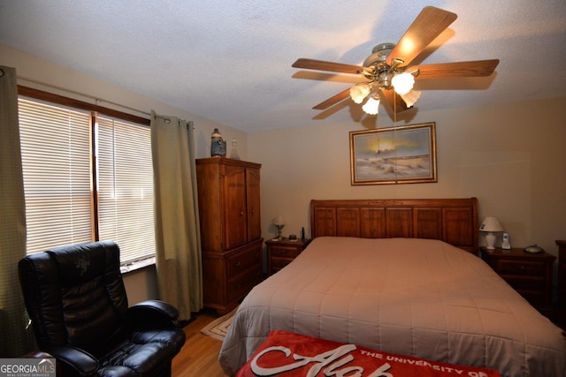 bedroom with a textured ceiling, multiple windows, light wood finished floors, and ceiling fan