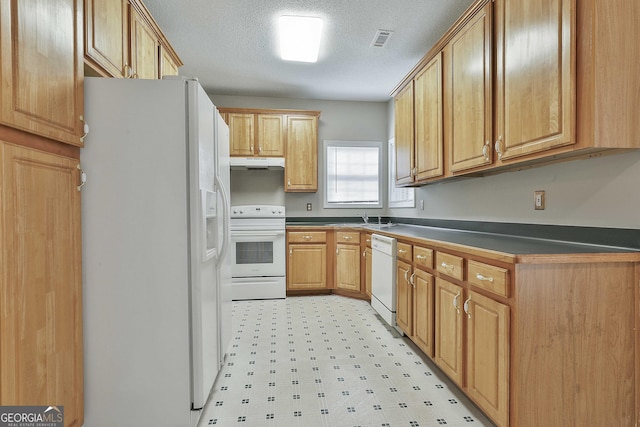 kitchen with dark countertops, visible vents, under cabinet range hood, light floors, and white appliances