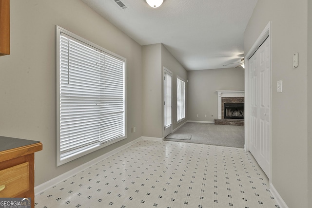 interior space with visible vents, baseboards, a stone fireplace, and ceiling fan