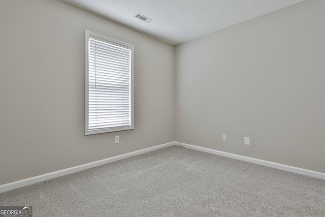 carpeted empty room with baseboards, visible vents, and a textured ceiling