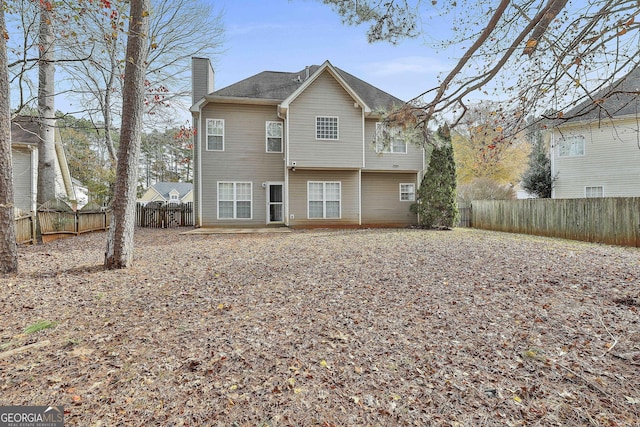 rear view of house with a fenced backyard and a chimney