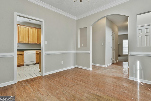 unfurnished dining area featuring baseboards, light wood finished floors, arched walkways, a textured ceiling, and crown molding