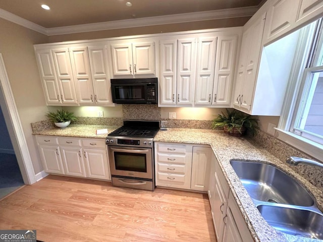 kitchen featuring a sink, light wood-style floors, black microwave, crown molding, and stainless steel gas range