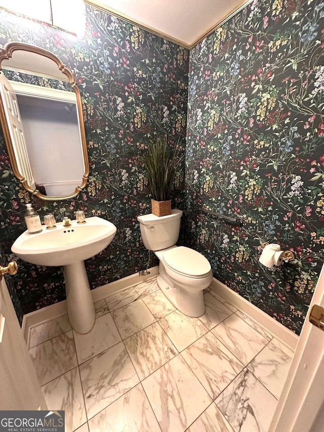 bathroom featuring marble finish floor, toilet, baseboards, and a sink