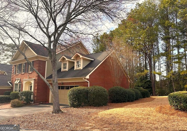 view of front facade with an attached garage, brick siding, and driveway