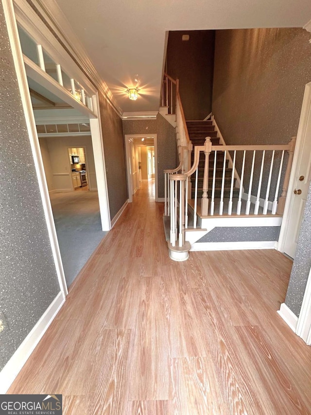 interior space featuring baseboards, wood finished floors, ornamental molding, and stairs