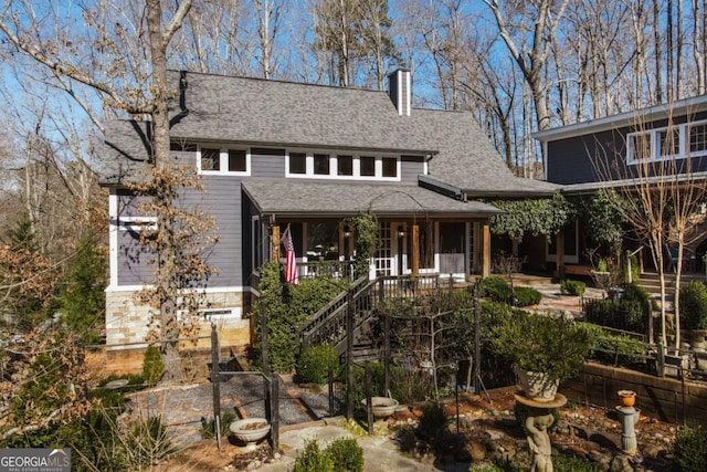 view of front of house featuring a shingled roof, stairway, and a chimney