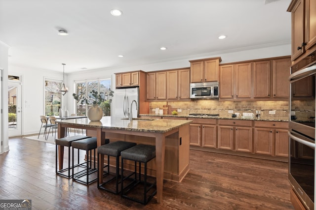 kitchen with a sink, decorative backsplash, appliances with stainless steel finishes, and brown cabinetry