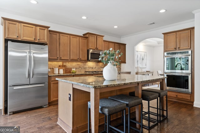 kitchen with visible vents, dark wood-type flooring, arched walkways, stone countertops, and stainless steel appliances