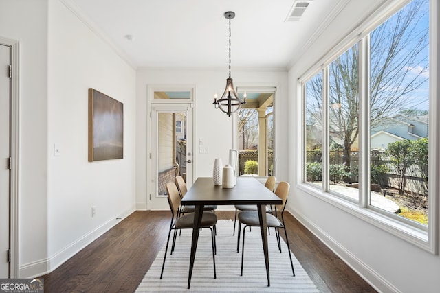 dining room with visible vents, crown molding, dark wood-type flooring, baseboards, and a notable chandelier