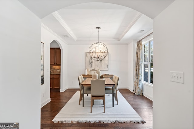 dining space featuring visible vents, dark wood finished floors, ornamental molding, a raised ceiling, and a notable chandelier