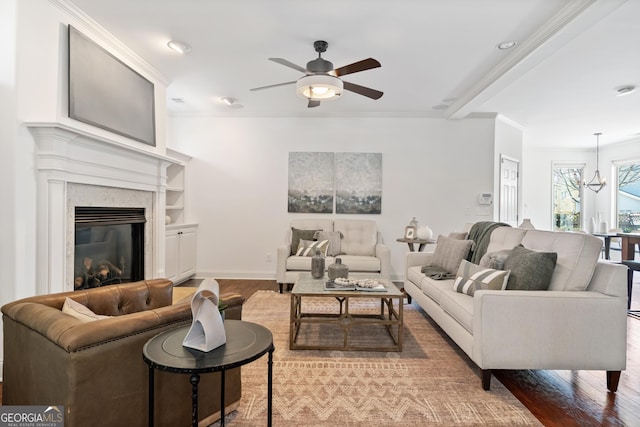 living room featuring a ceiling fan, wood finished floors, a high end fireplace, crown molding, and baseboards