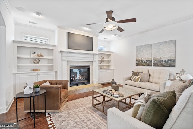 living area featuring visible vents, ornamental molding, wood finished floors, baseboards, and ceiling fan