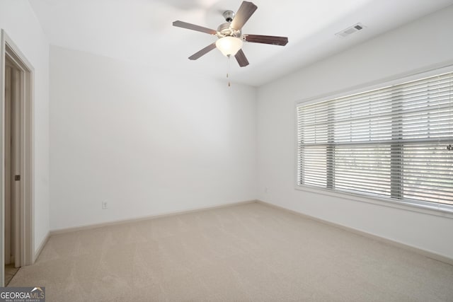 unfurnished room featuring visible vents, light carpet, baseboards, and a ceiling fan