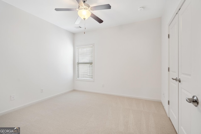 spare room with visible vents, baseboards, light colored carpet, and a ceiling fan