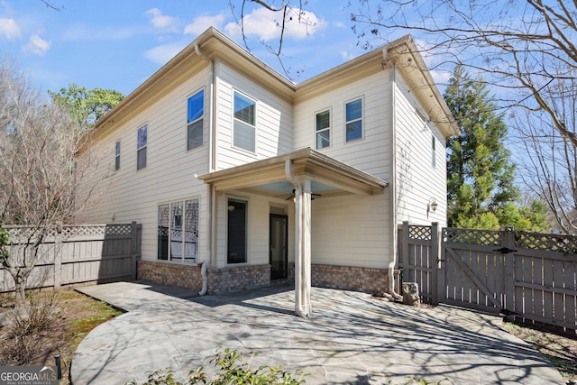 view of front of home featuring a patio area, a gate, fence, and brick siding