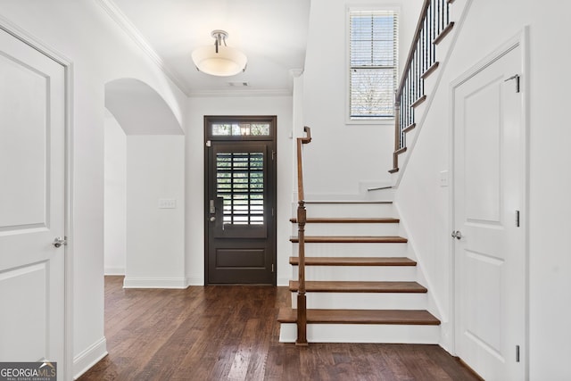 foyer featuring visible vents, ornamental molding, wood finished floors, baseboards, and stairs