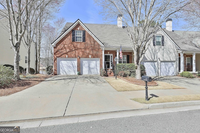 traditional-style house with a garage, brick siding, driveway, and a chimney