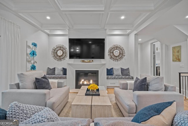 living area featuring beamed ceiling, recessed lighting, light wood-style flooring, a glass covered fireplace, and coffered ceiling