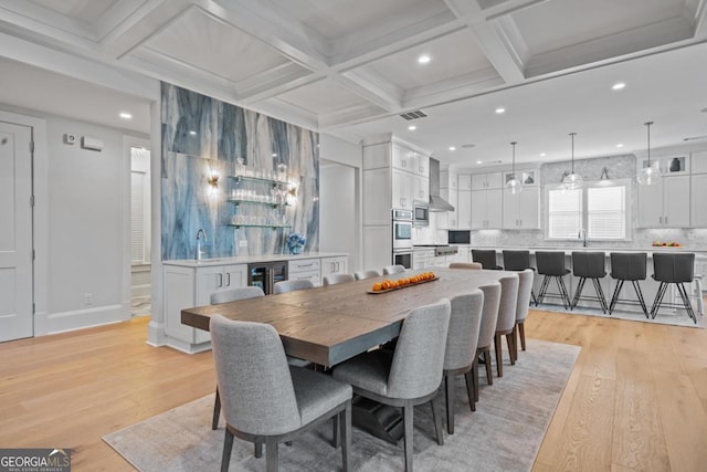 dining area featuring visible vents, wine cooler, beam ceiling, light wood-style flooring, and coffered ceiling