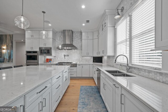 kitchen featuring stainless steel appliances, light wood finished floors, visible vents, and wall chimney range hood