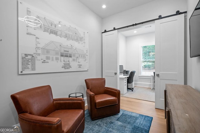 living area with recessed lighting, baseboards, light wood-type flooring, and a barn door