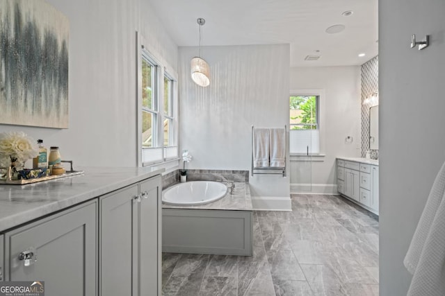 bathroom featuring a bath, baseboards, and two vanities