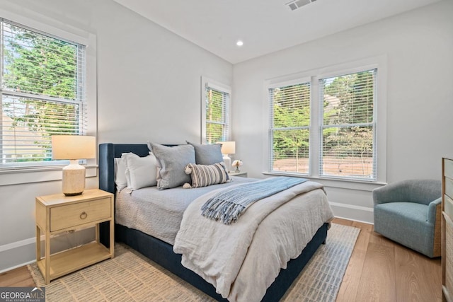 bedroom with recessed lighting, multiple windows, wood finished floors, and baseboards