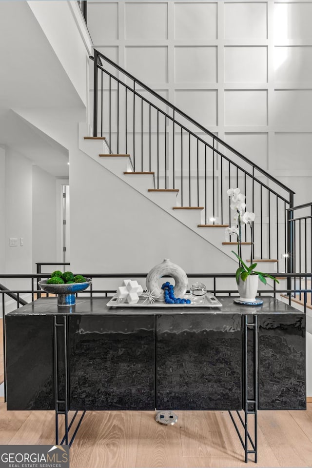 stairway with a decorative wall and wood finished floors