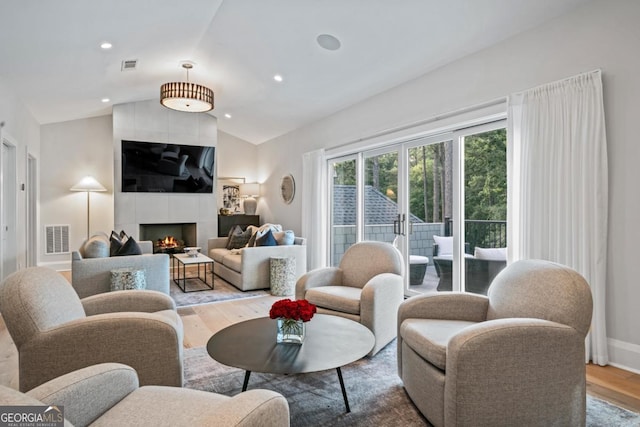 living room with a fireplace, vaulted ceiling, wood finished floors, and visible vents