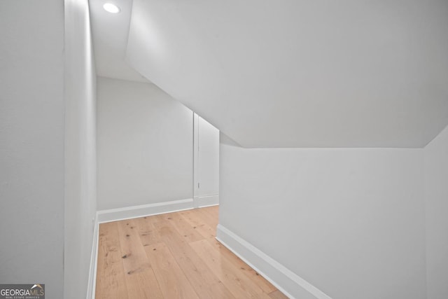 additional living space with vaulted ceiling, light wood-style floors, and baseboards