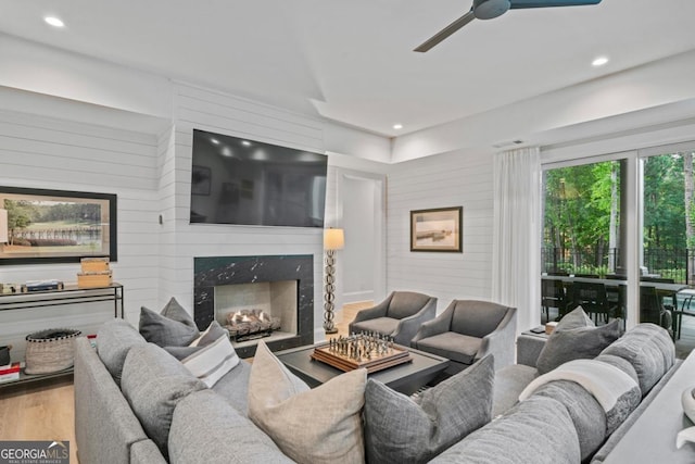 living room with recessed lighting, wood finished floors, a ceiling fan, and a premium fireplace